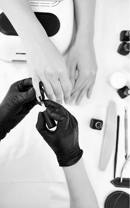 Maître manucure en gants noirs appliquant du gel-lac sur les ongles de la cliente